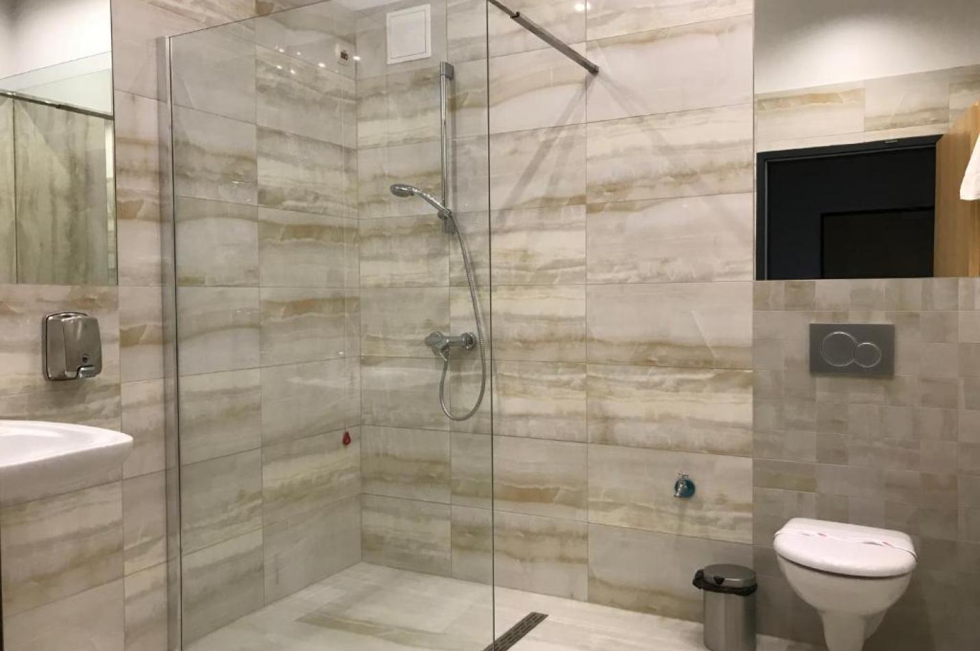 Nowoczesna łazienka z umywalką, sedesem i przeszklonym prysznicem.