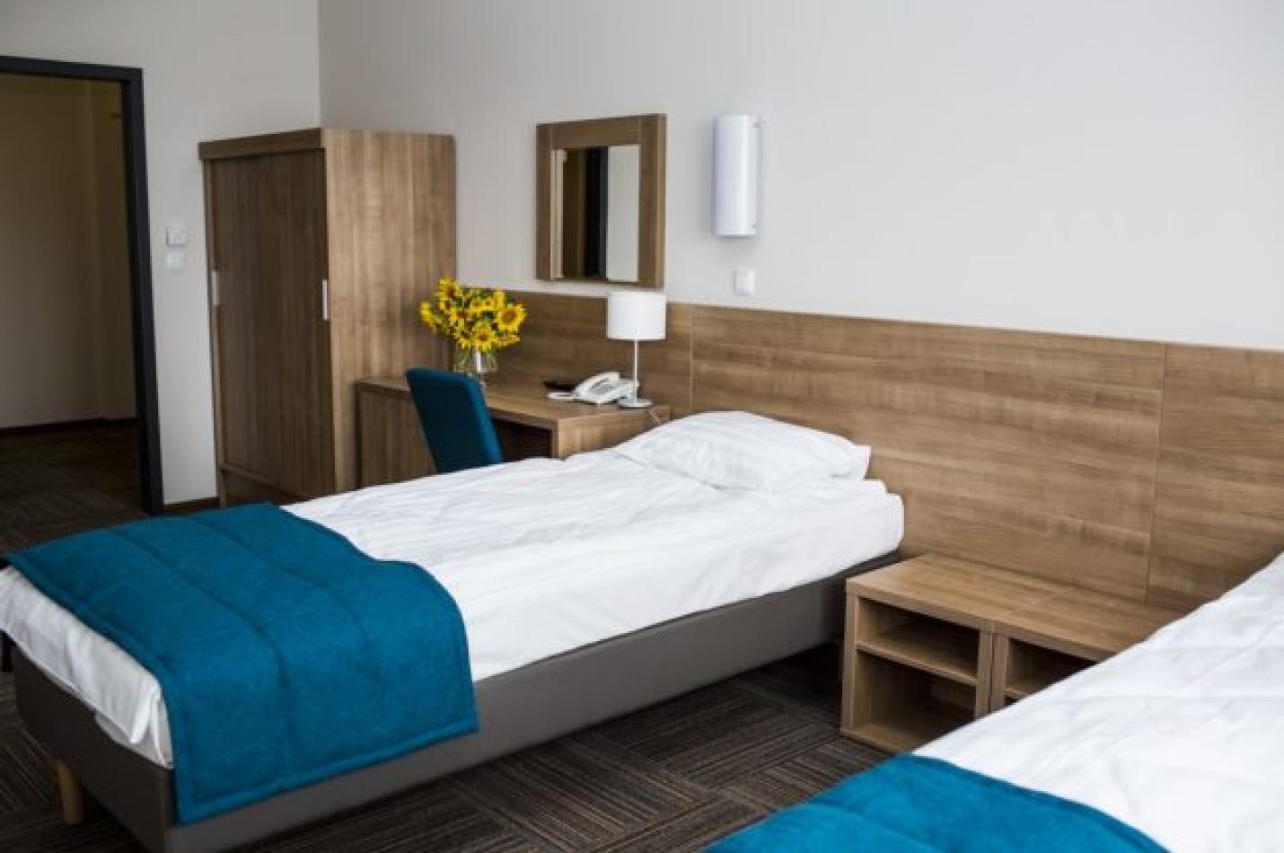 Dwuosobowy pokój z łóżkami, biurkiem i szafą.