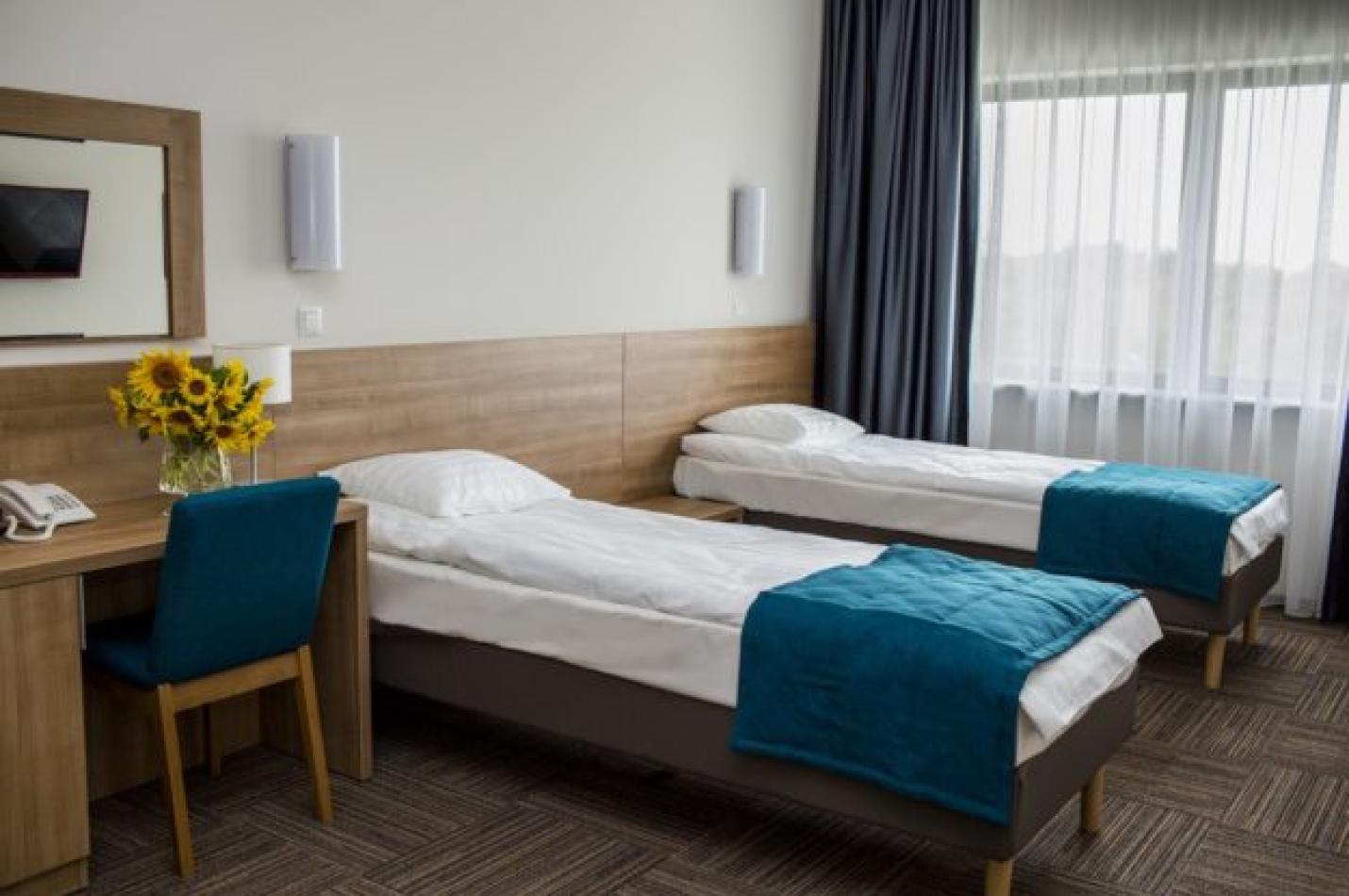 Pokój dwuosobowy z łóżkami i biurkiem.