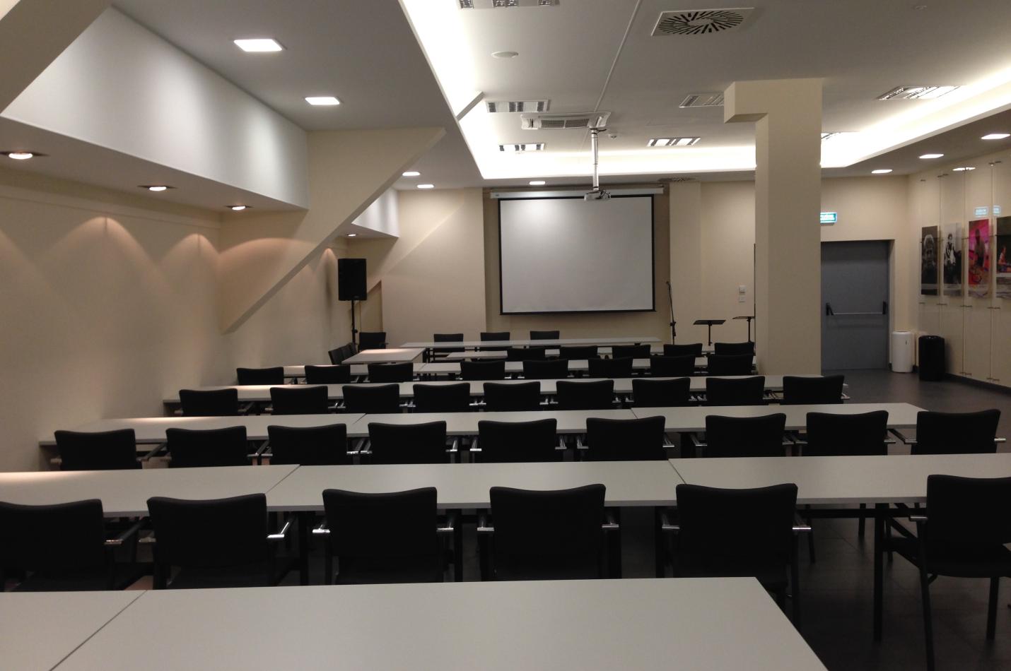 Duże pomieszczenie z ustawionymi stołami i krzesłami.