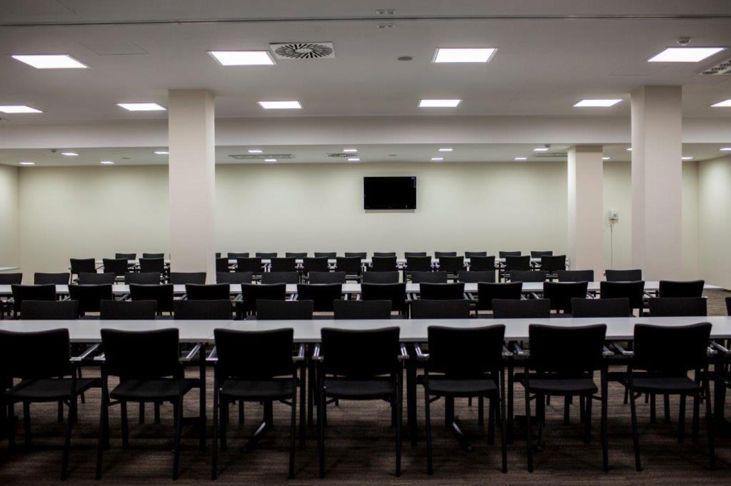 Elegancka sala konferencyjna z ustawionymi stołami i krzesłami.