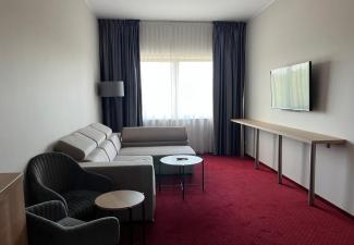 Duże pomieszczenie z kanapą, fotelami i stolikami kawowymi oraz telewizorem.