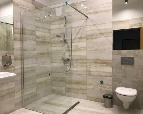 Nowoczesna łazienka z umywalką, sedesem i przeszklonym prysznicem.