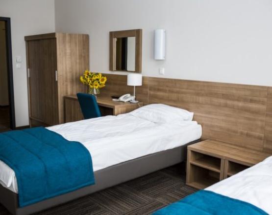 Duży pokój z łóżkami, biurkiem i szafą.