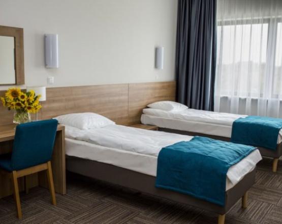 Pokój dwuosobowy z łóżkami i biurkiem.