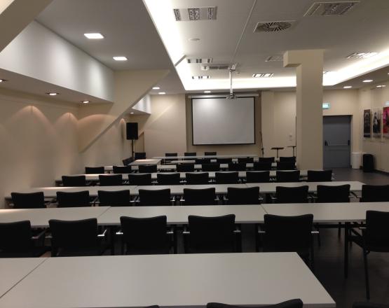 Duże pomieszczenie z ustawionymi stołami i krzesłami.